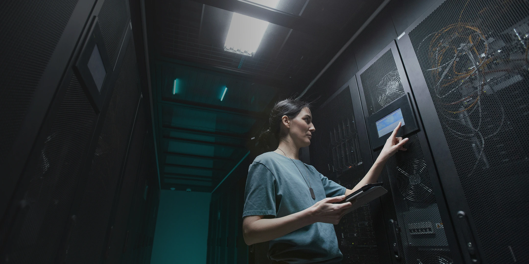 Woman with a tablet inspecting equipment in a server room.