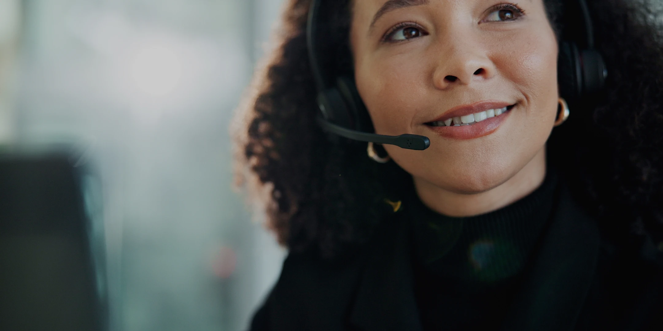 Close-up of a friendly female customer support agent wearing a headset, ready to assist customers.
