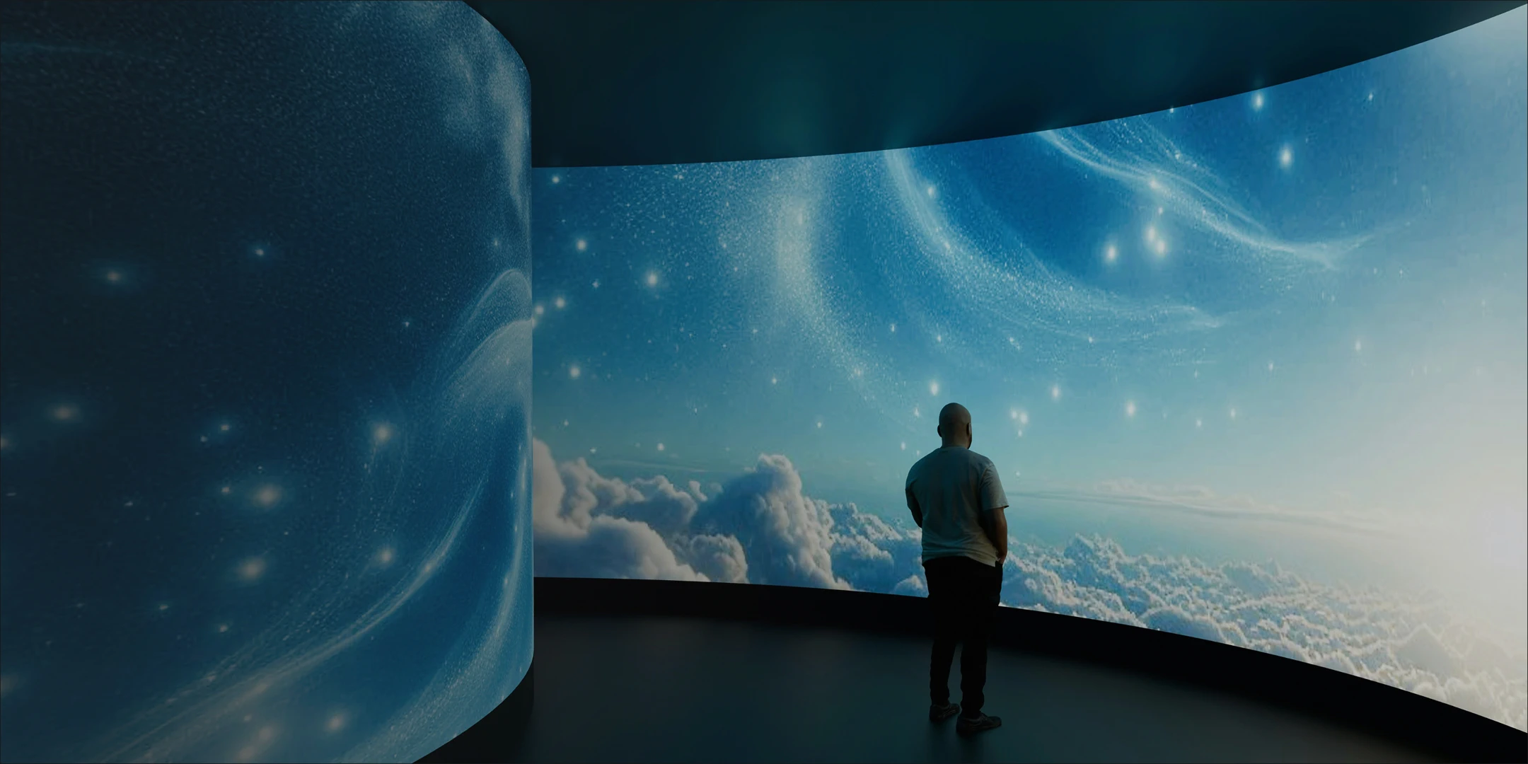 Man looking at a large screen displaying clouds and sky.