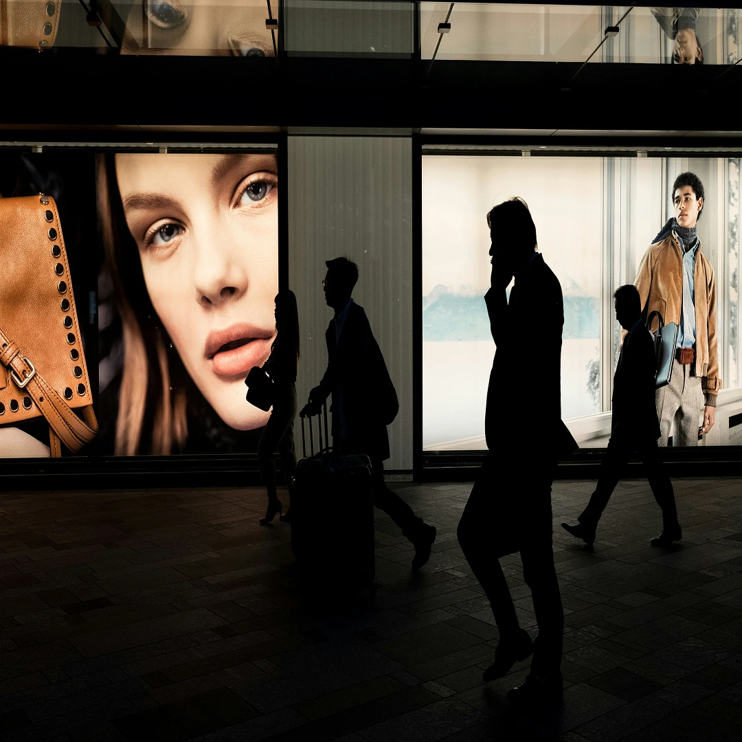 Shoppers passing a storefront with displays of fashion items