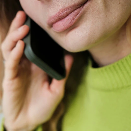 Close-up of a person holding a mobile phone to their ear.