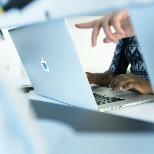Close-up of a hand pointing at a laptop screen.
