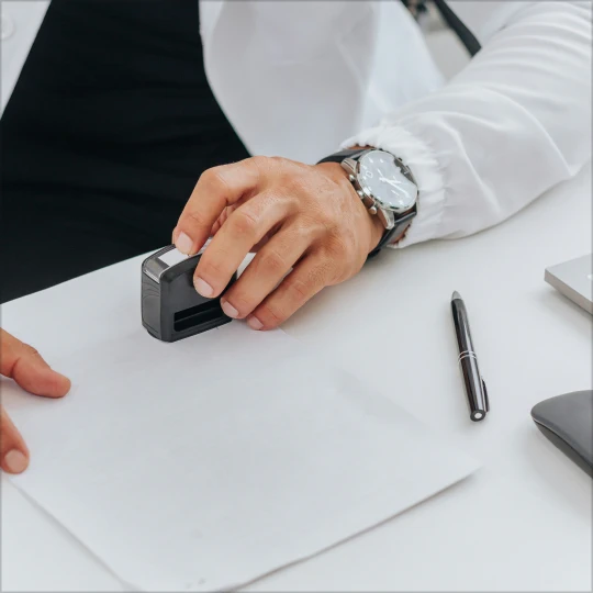 A man in a white suit is stamping documents on a white table.
