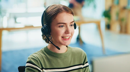 Smiling woman in a green shirt and headset, providing customer support