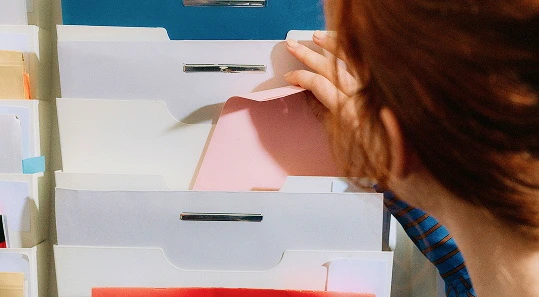 A woman with red hair is organizing documents into folders.