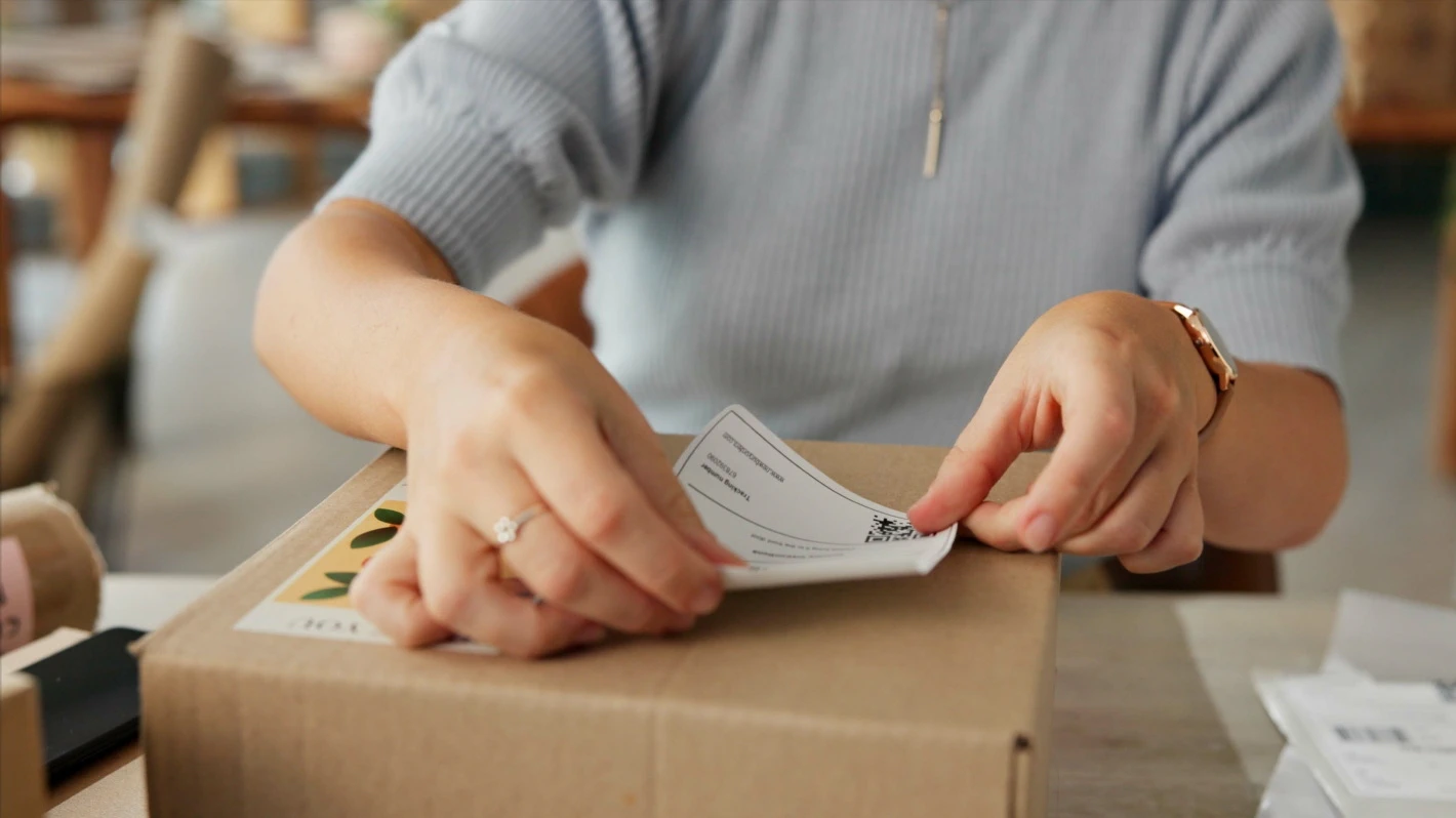 Woman's hands applying a shipping label to a cardboard box