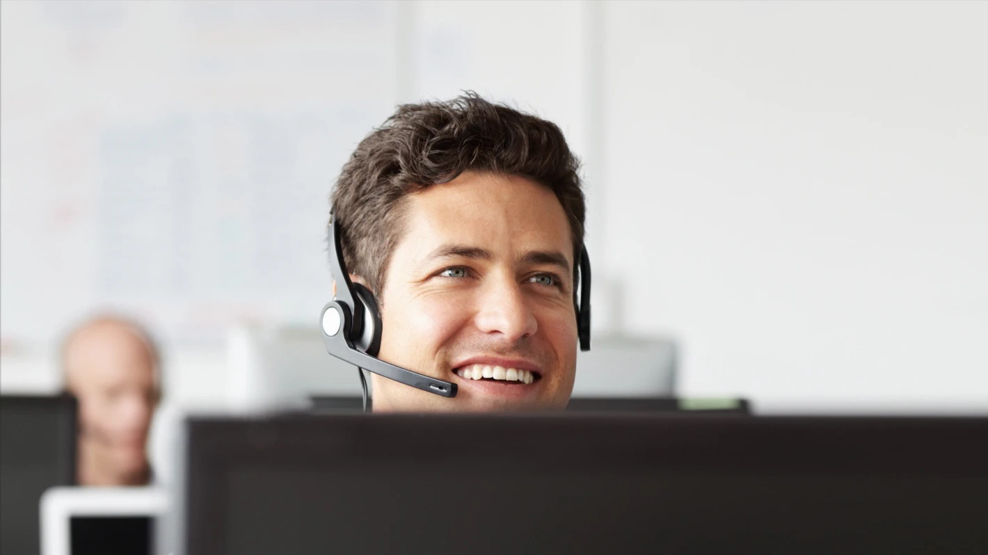 A friendly, smiling male customer service representative wearing a headset