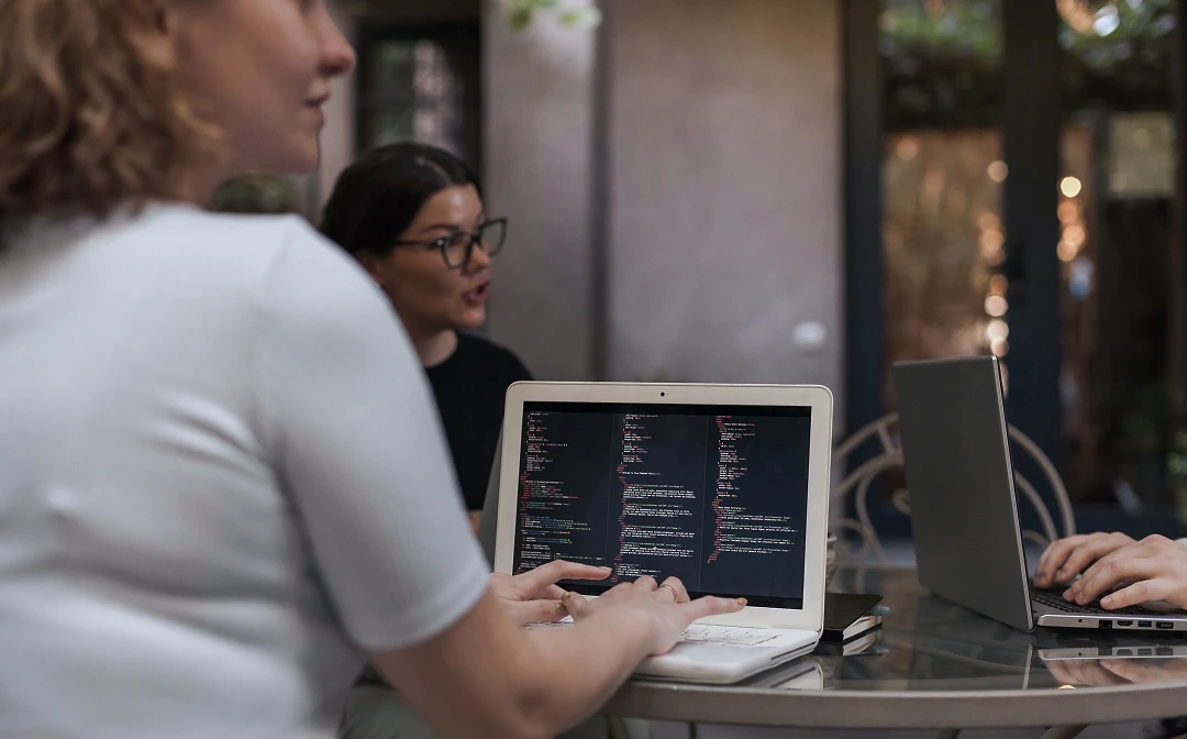 Three medical billing specialists working on laptops and collaborating in an office setting