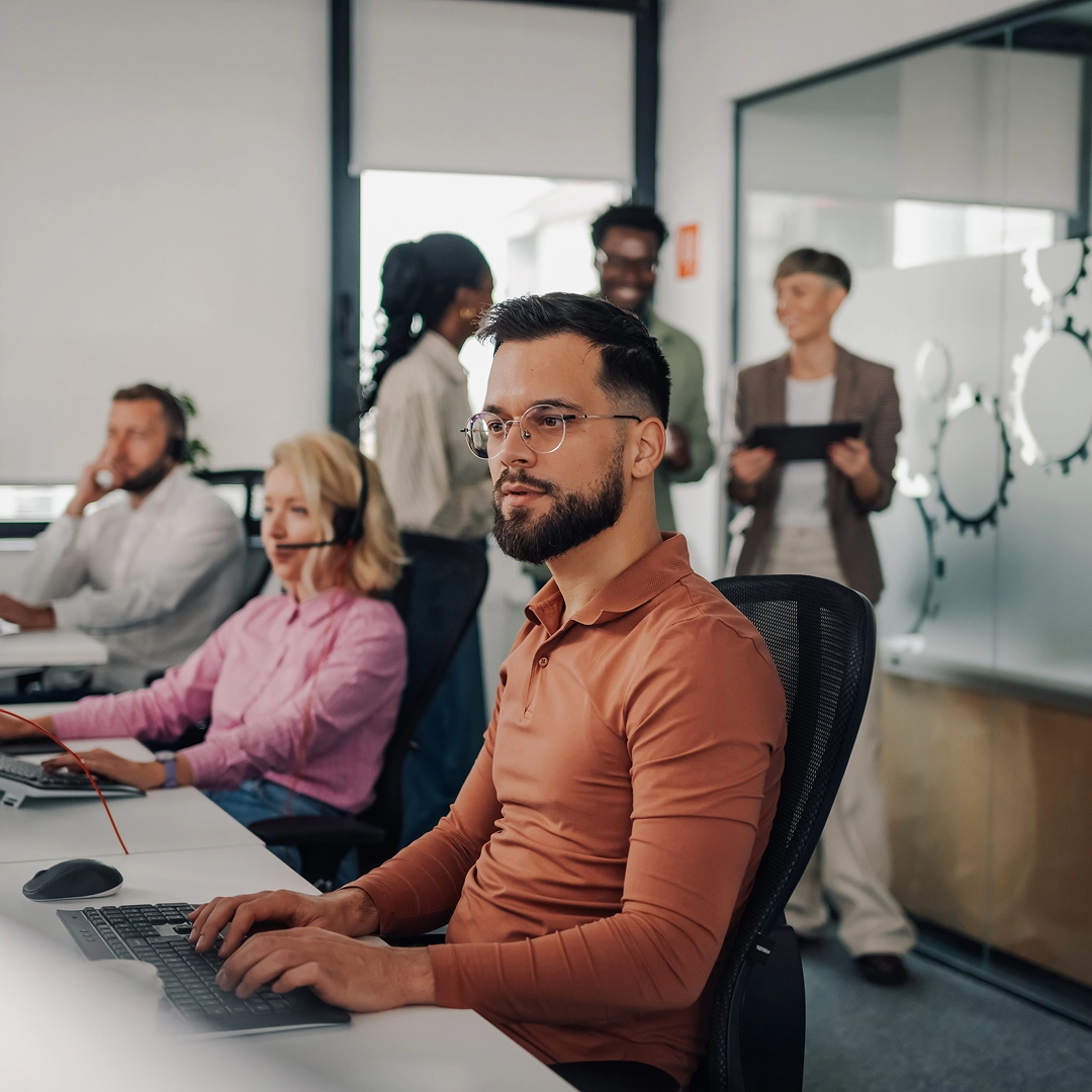 Mexican customer support team providing assistance in a modern office environment with headsets and computers