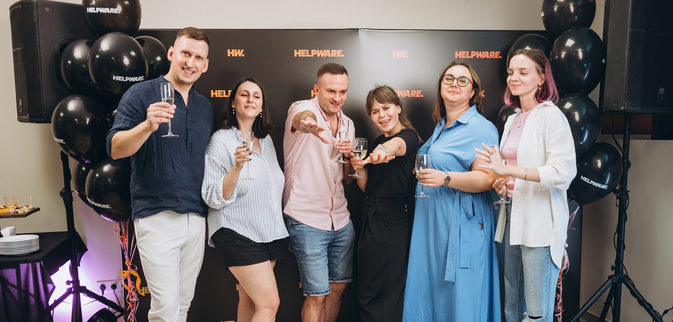 Enthusiastic Helpware employees toasting with champagne at a company celebration.