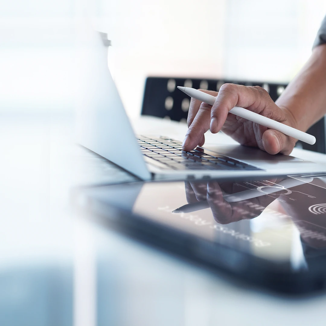 Close-up of a man’s hand holding a stylus while working on a laptop