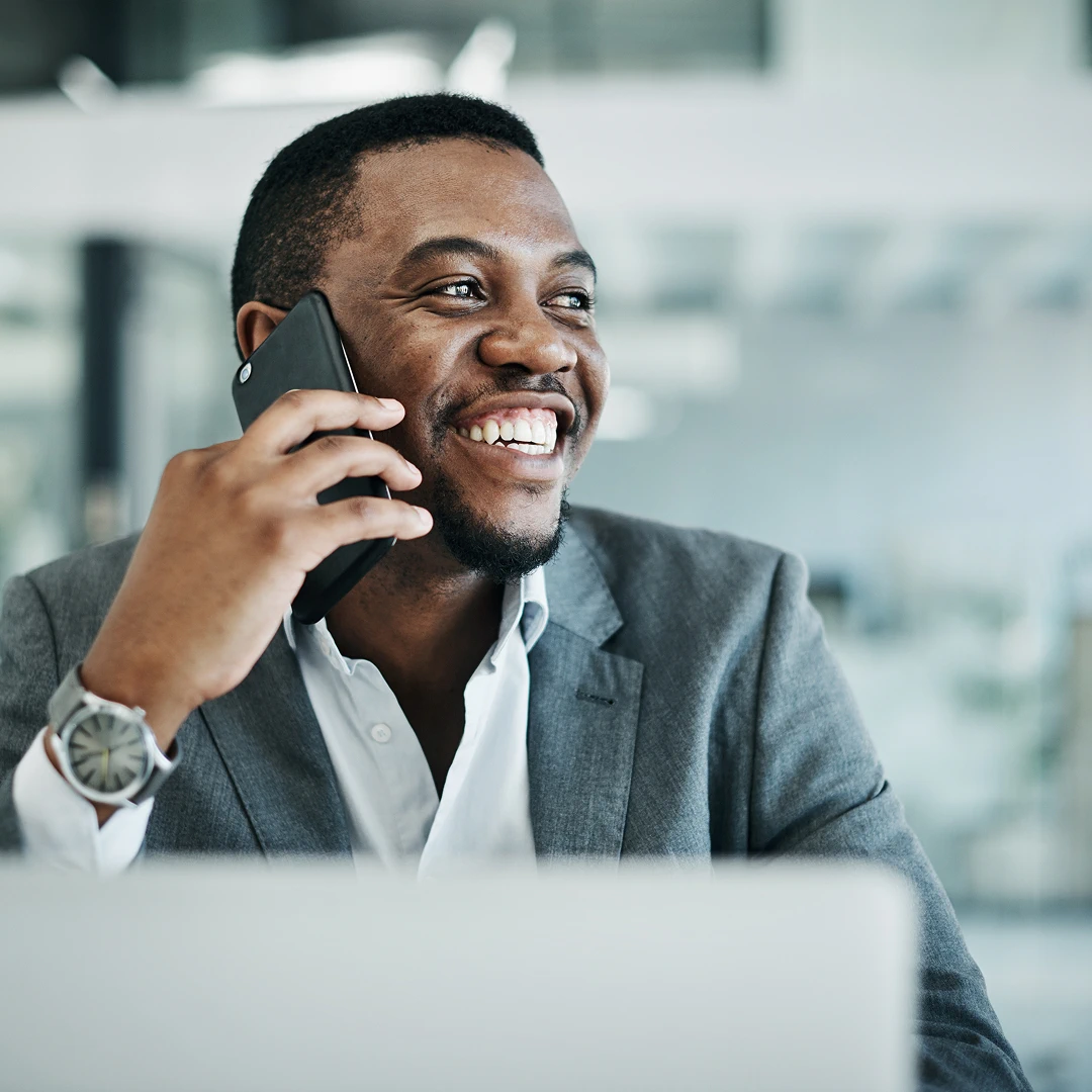 Smiling man in a suit enthusiastically talks on his phone