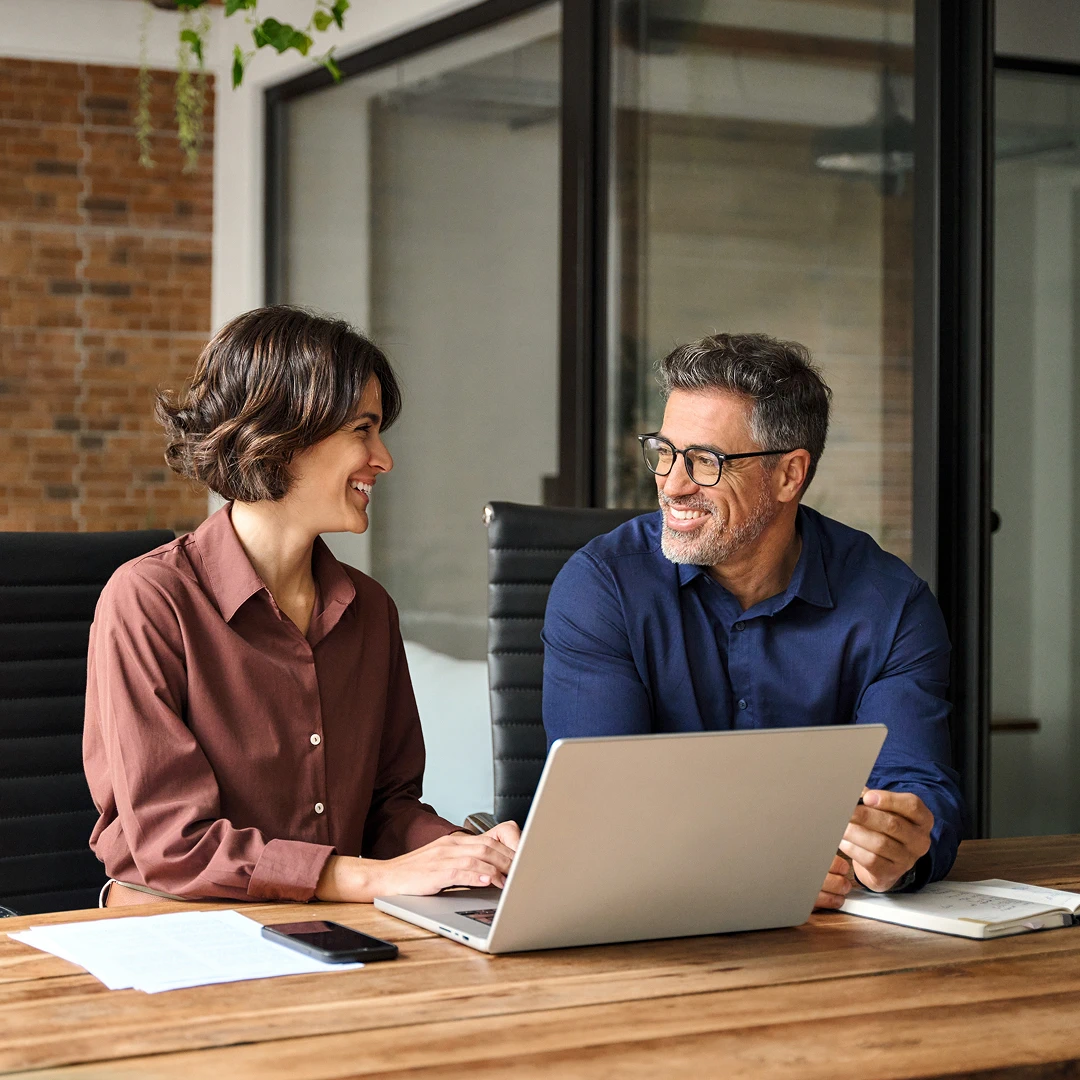 Smiling man and woman collaborating on a laptop in a modern office