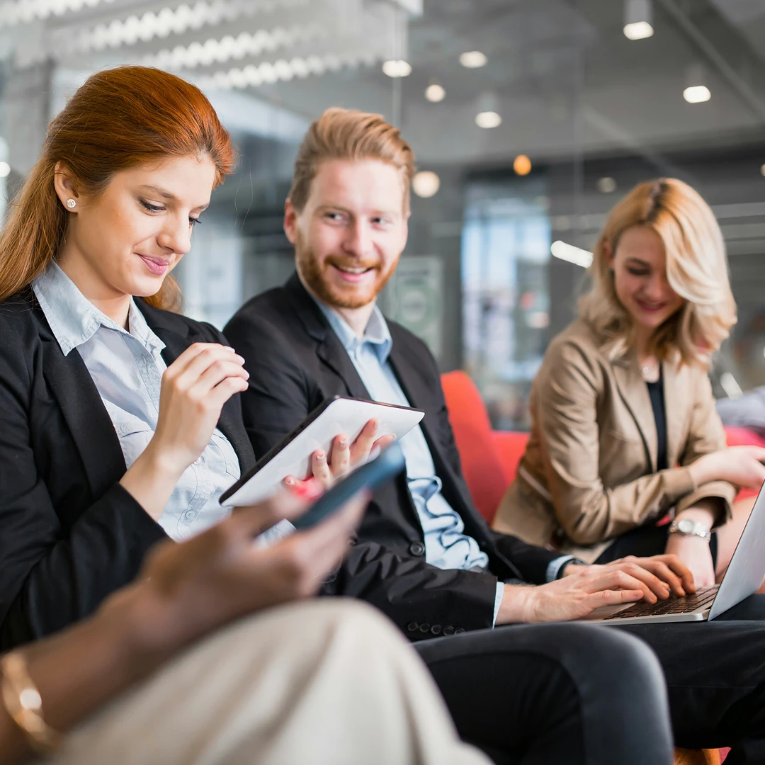 Group of businesspeople working on laptops and tablets in a modern office setting