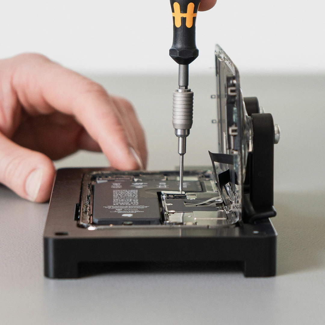 Close-up of male hands repairing a computer hard drive with a screwdriver