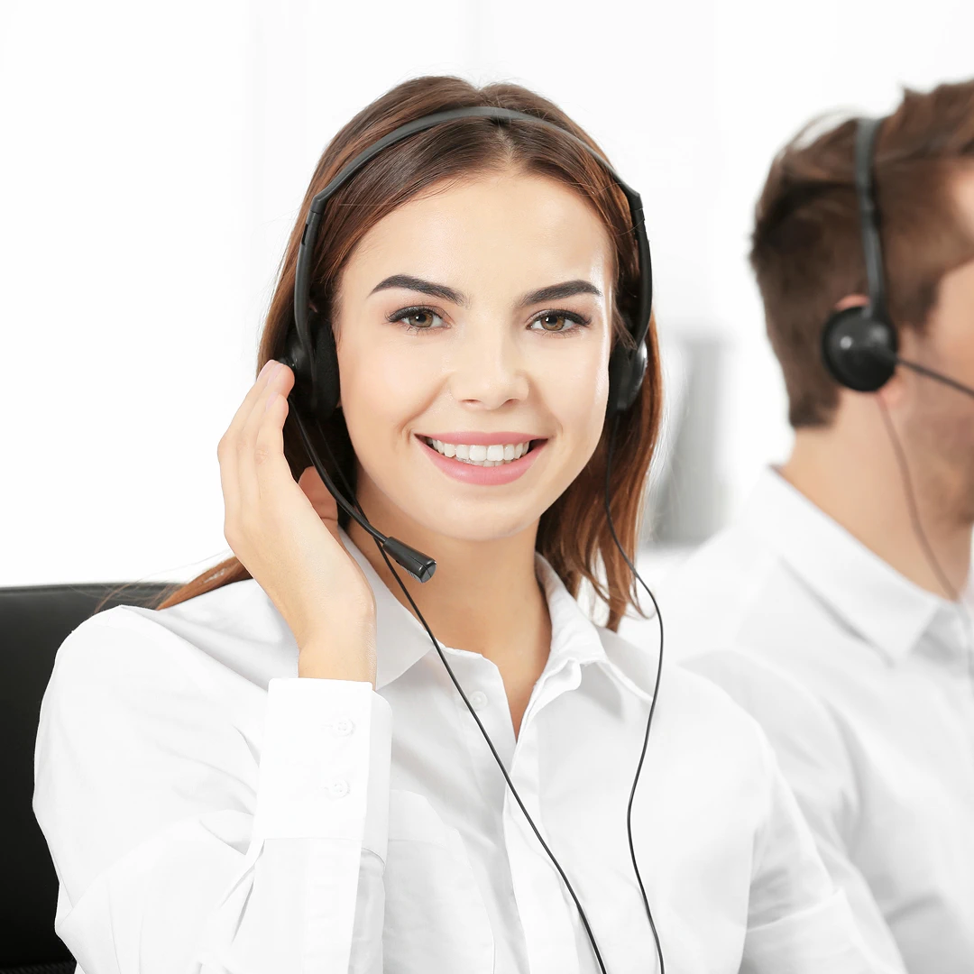 Friendly female customer support agent with brown hair is wearing a white blouse and a headset