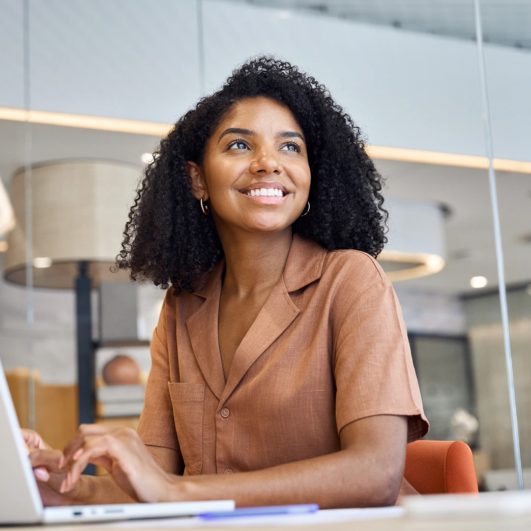 Woman in brown blouse working on laptop in a stylish contemporary office