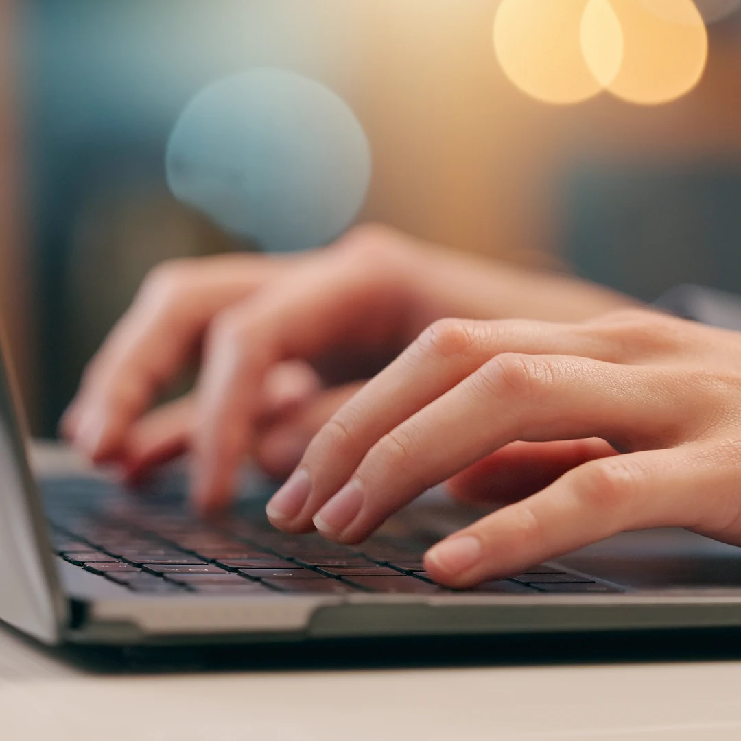 Close-up of a man's hands working on a laptop
