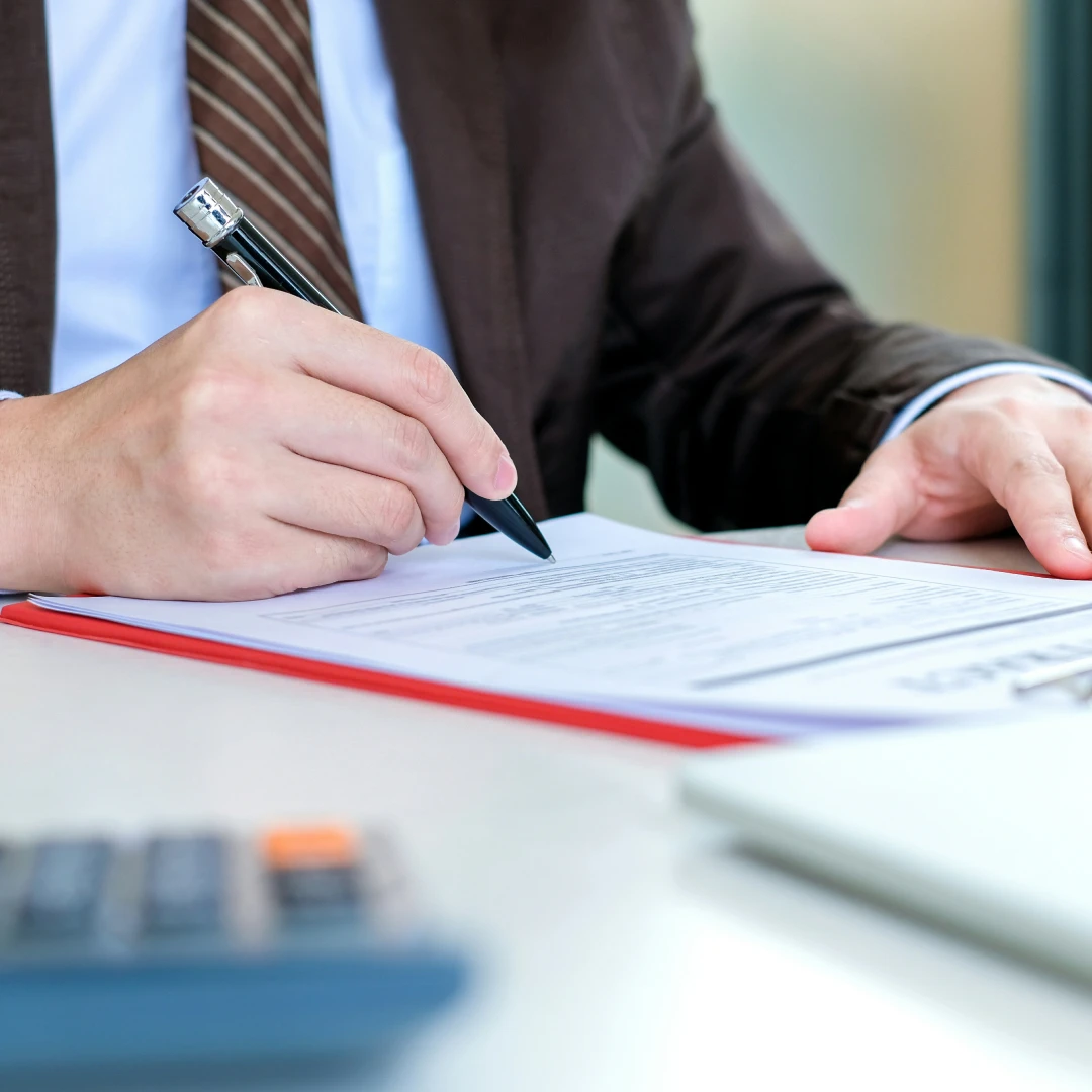 Man in business attire signing a contract with a pen
