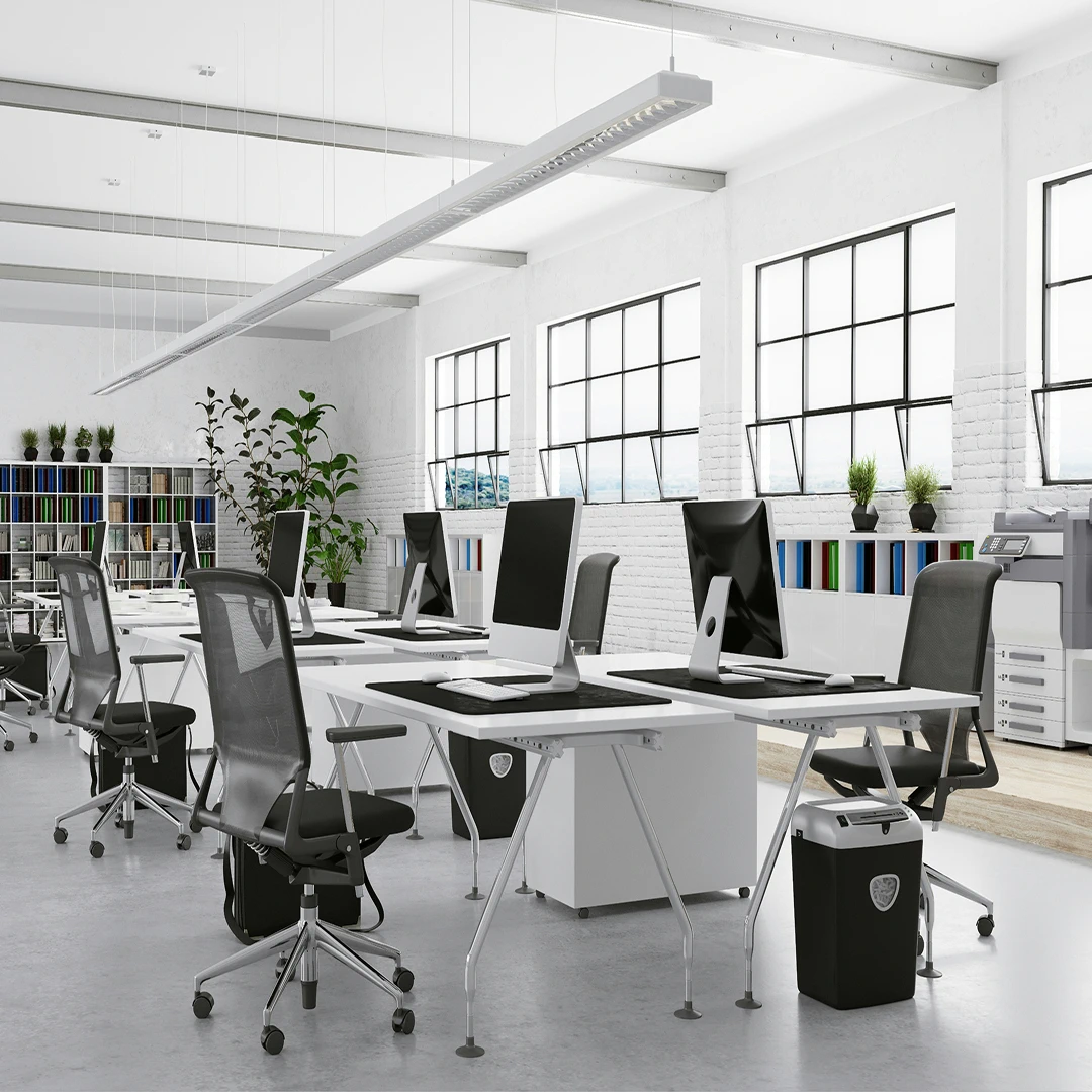 A bright, open office with white desks, black chairs, and large windows
