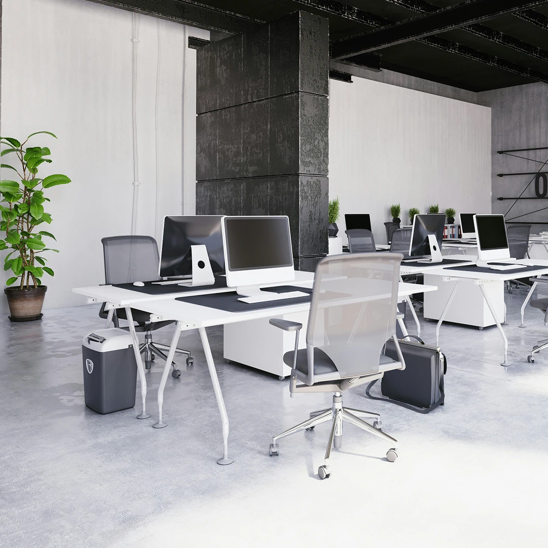 An empty modern office featuring desks with desktop computers and rolling chairs