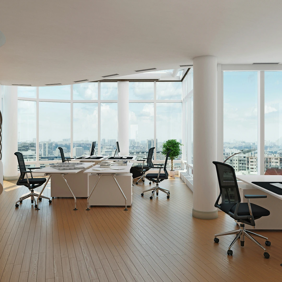 Bright, open office with large windows overlooking a cityscape, featuring white desks and black office chairs
