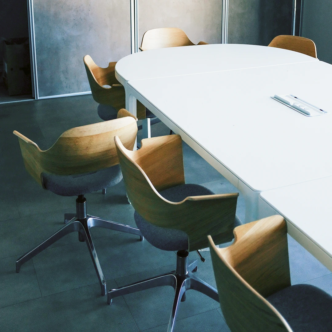 Modern, minimalist conference room with a white oval table and wooden chairs
