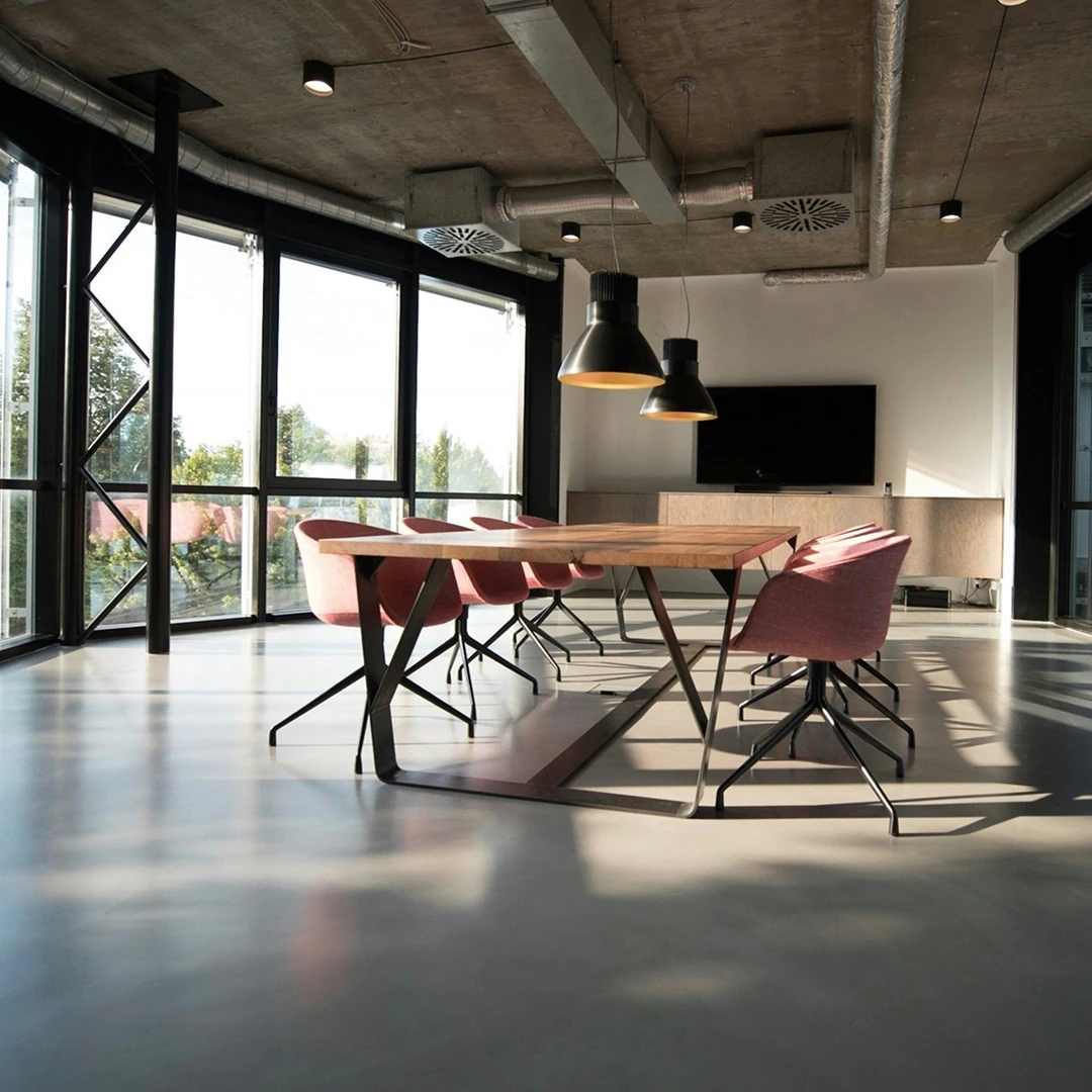 Modern conference room with a large wooden table, pink chairs, and large windows