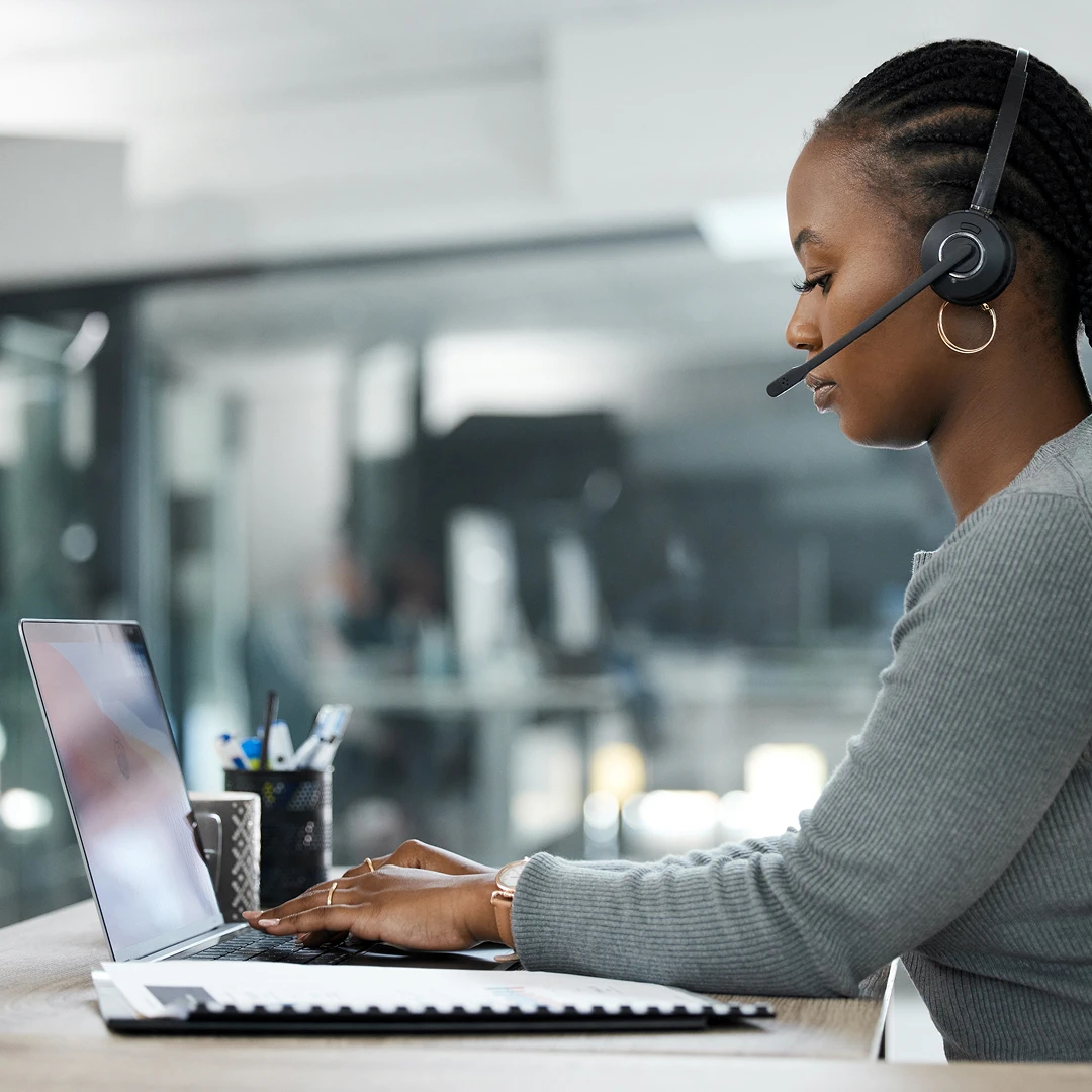 Woman call center agent assisting clients using laptop and headset