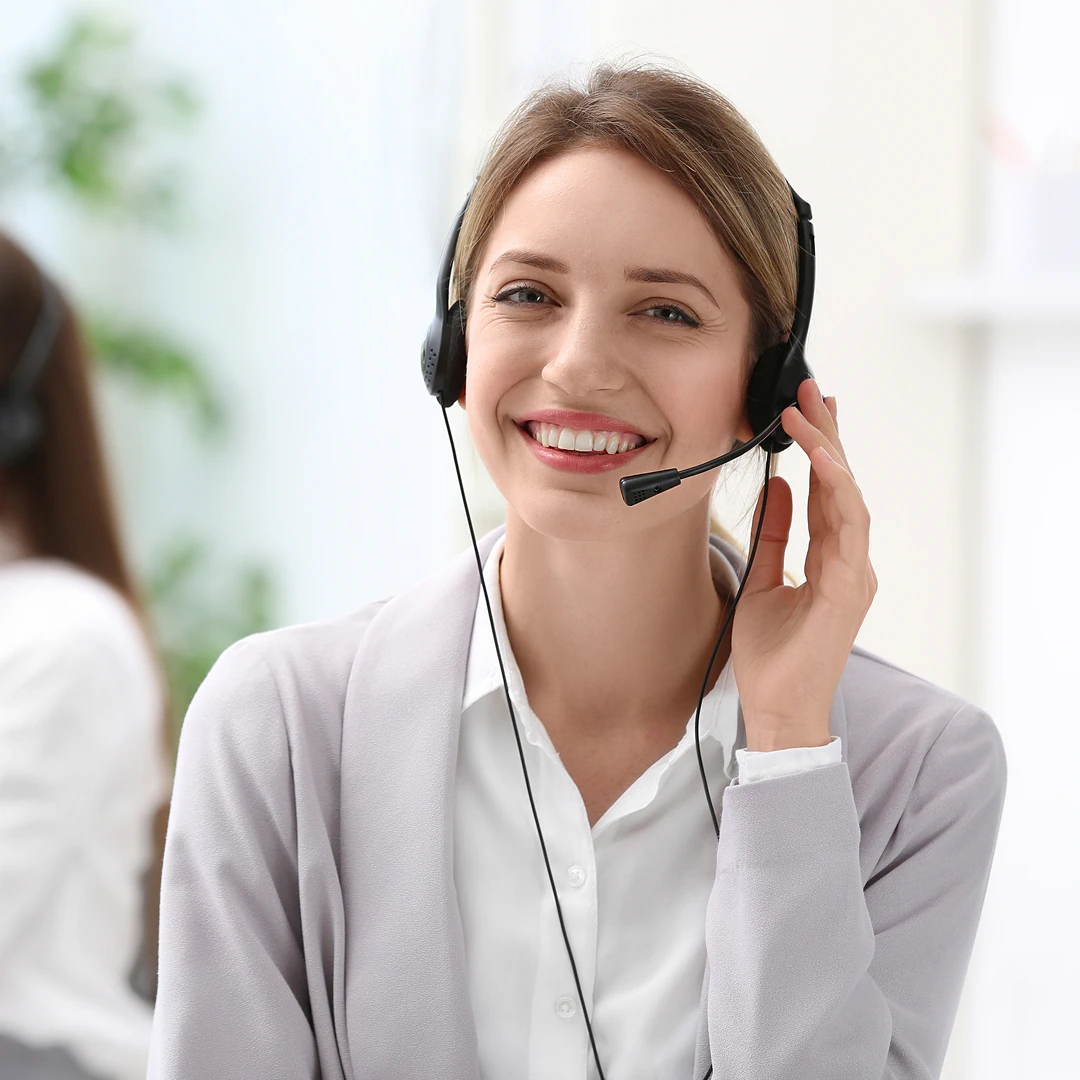Blonde female customer support representative smiling, wearing a headset and a grey blazer