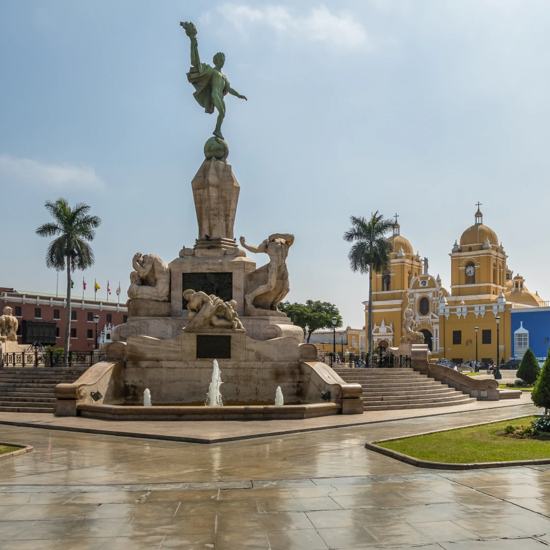 Monument to the Liberators in Trujillo, Peru, with fountains and statues, set against the backdrop of the Santo Domingo Church