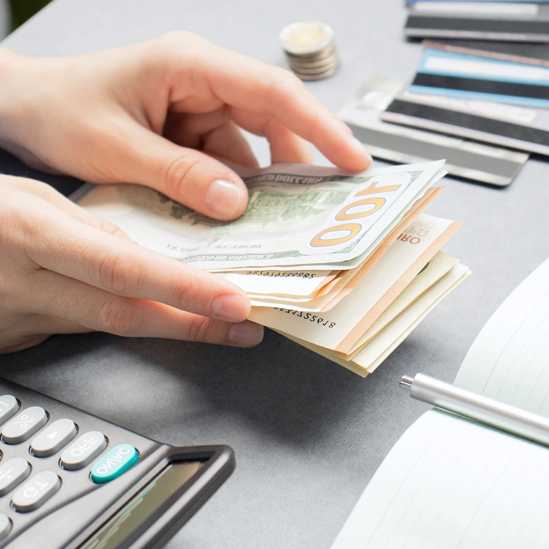 Hands counting a stack of US dollars and Euro banknotes