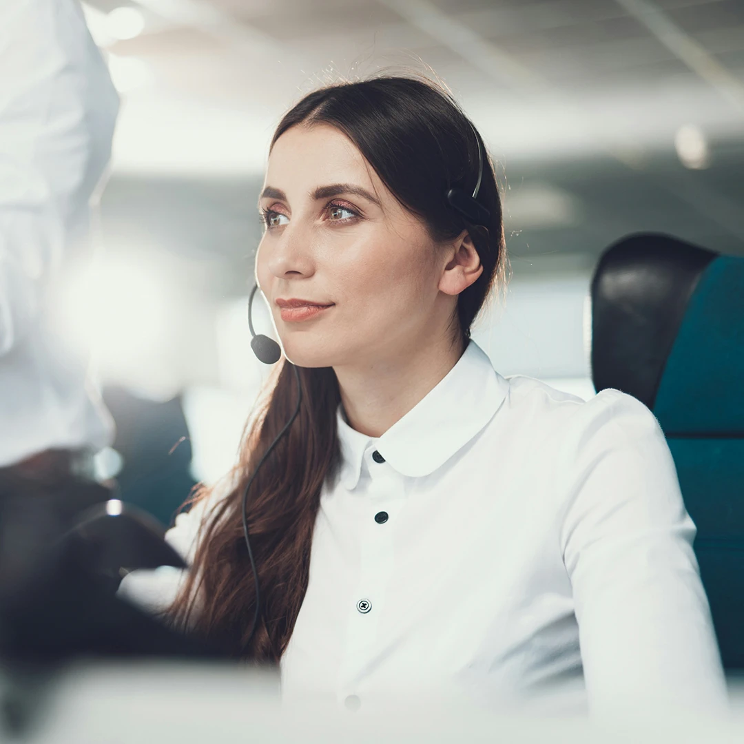A woman with long dark hair wearing a headset in a modern office