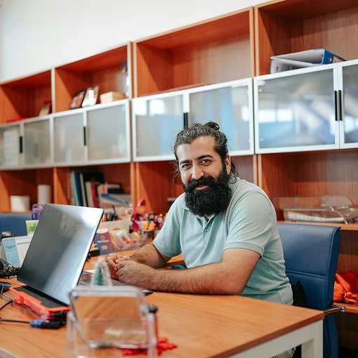 Smiling man in light green t-shirt working on laptop at desk