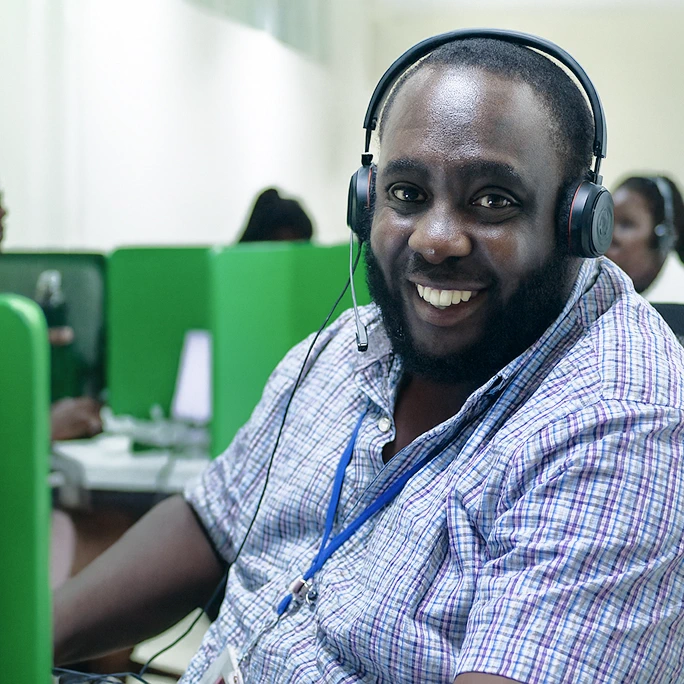 A smiling support representative wearing a light blue shirt and a headset.