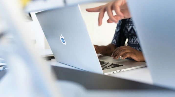 a finger pointing at a macbook screen