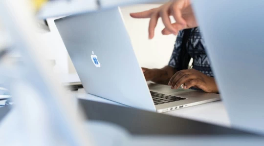 a finger pointing at a macbook