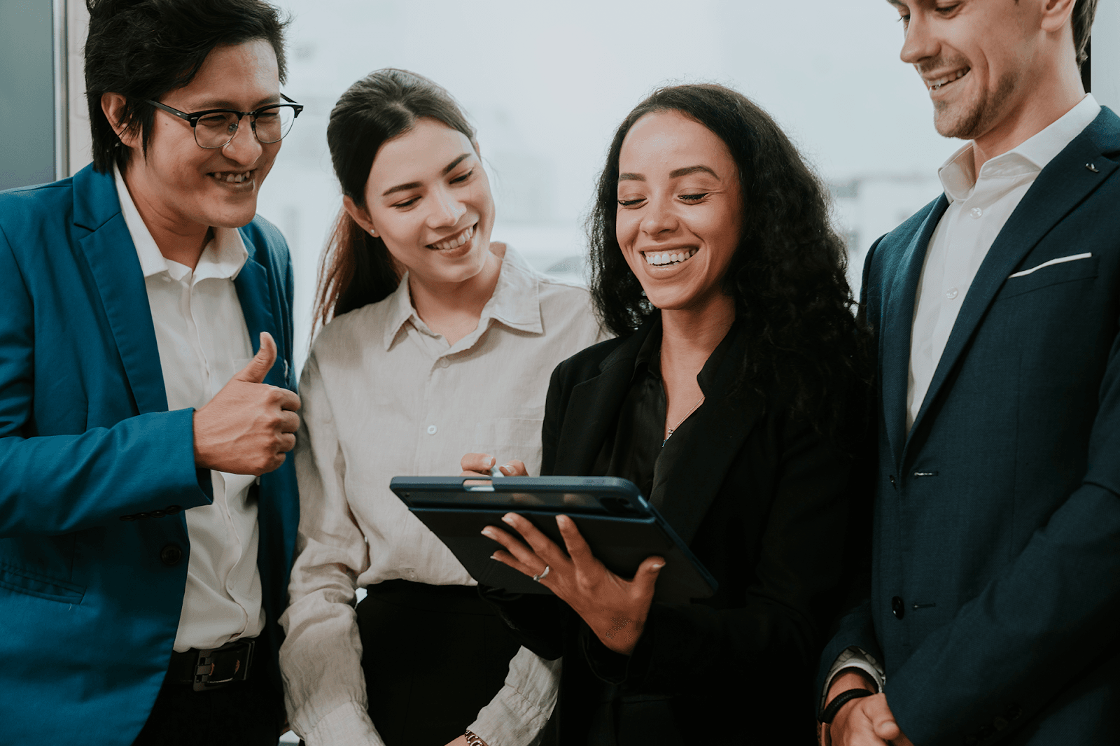 A team of colleagues collaborates and shares ideas while looking at information on a tablet device.