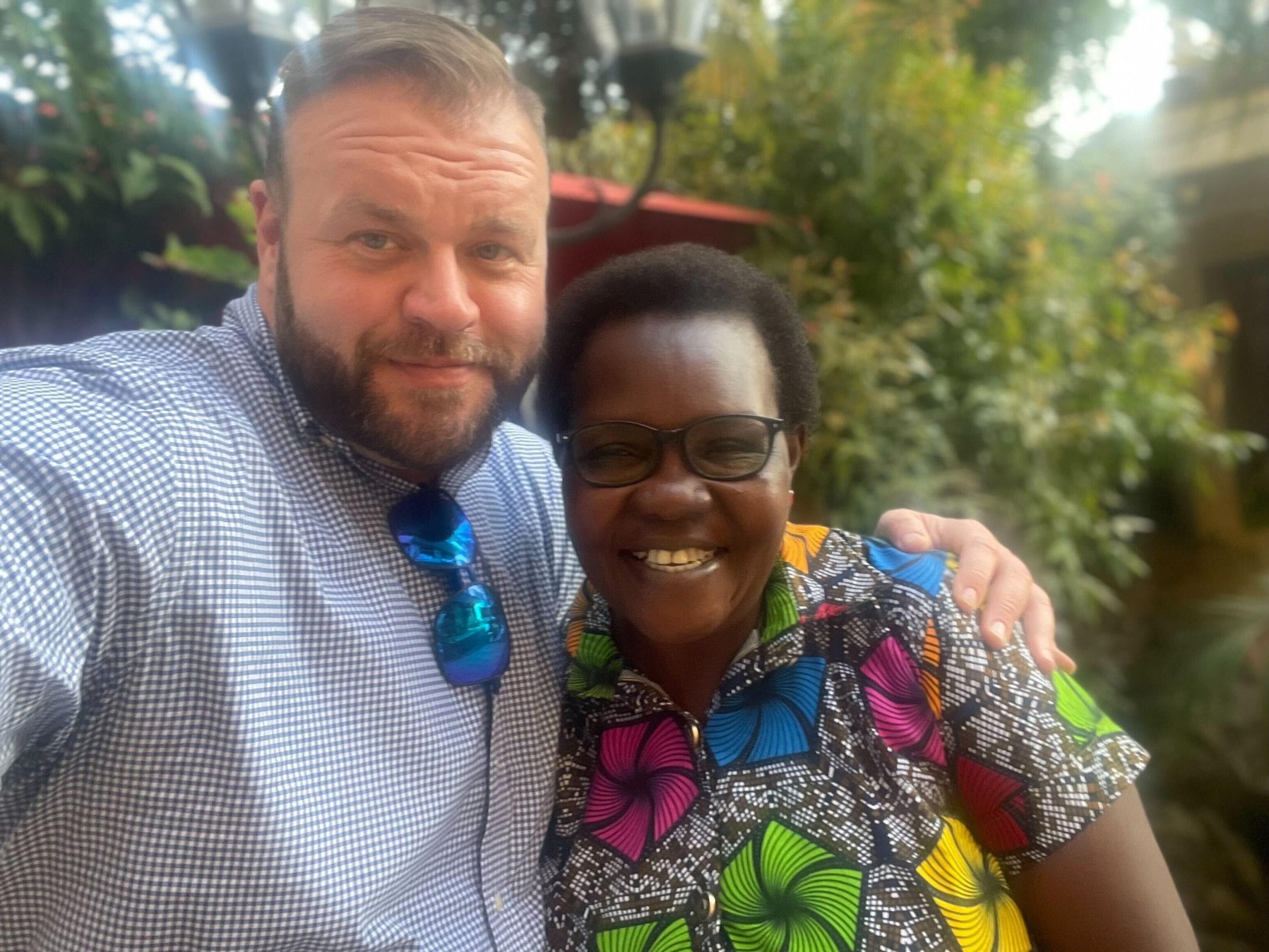 CEO of Helpware, Robert Nash, takes a selfie with a woman with short curly hair wearing a multicolored blouse
