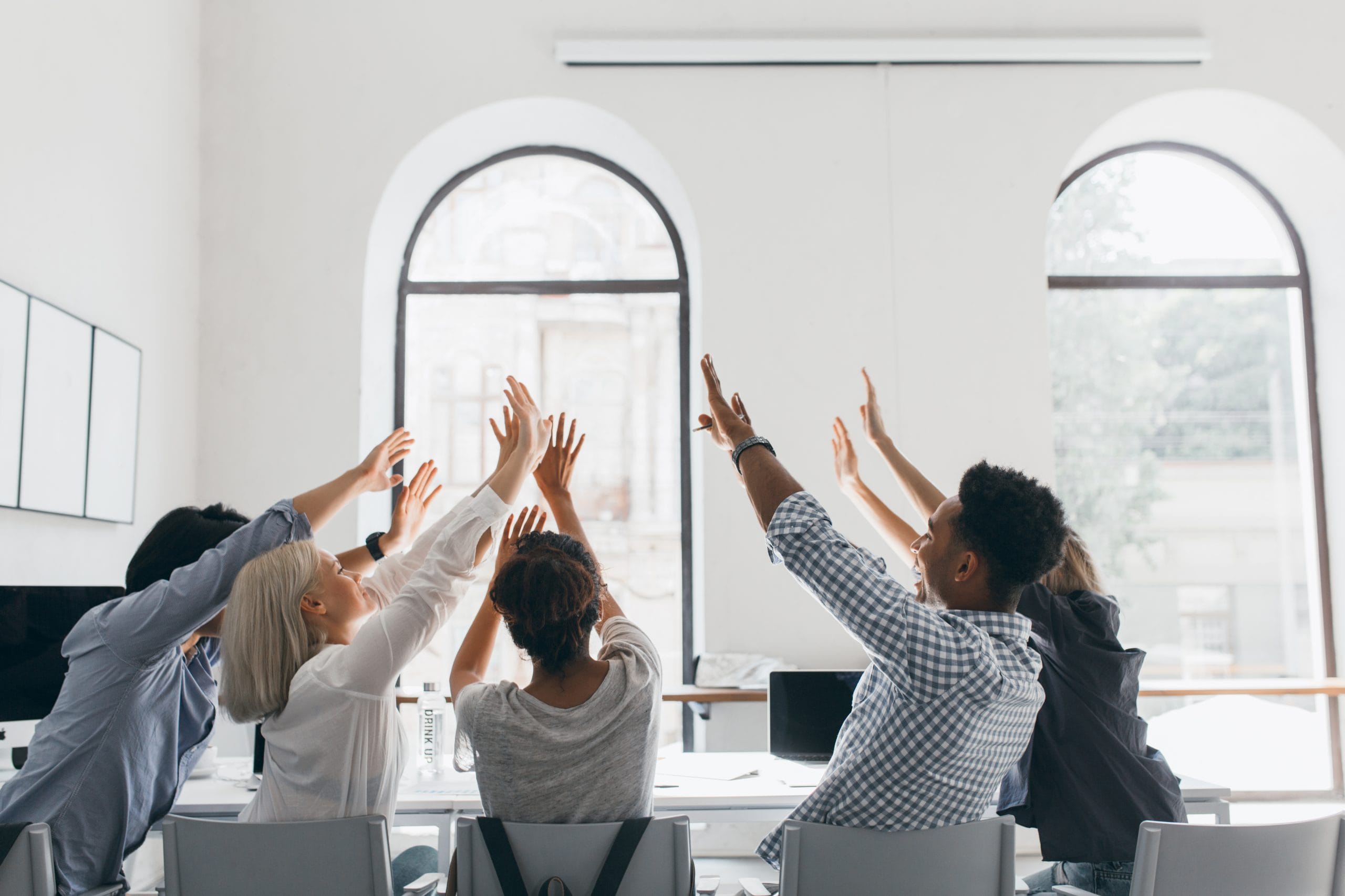 A team celebrates a success with a high-five in a bright office