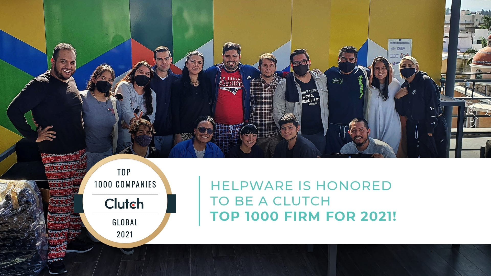 Helpware team members posing for a photo in front of a colorful wall, many wearing masks