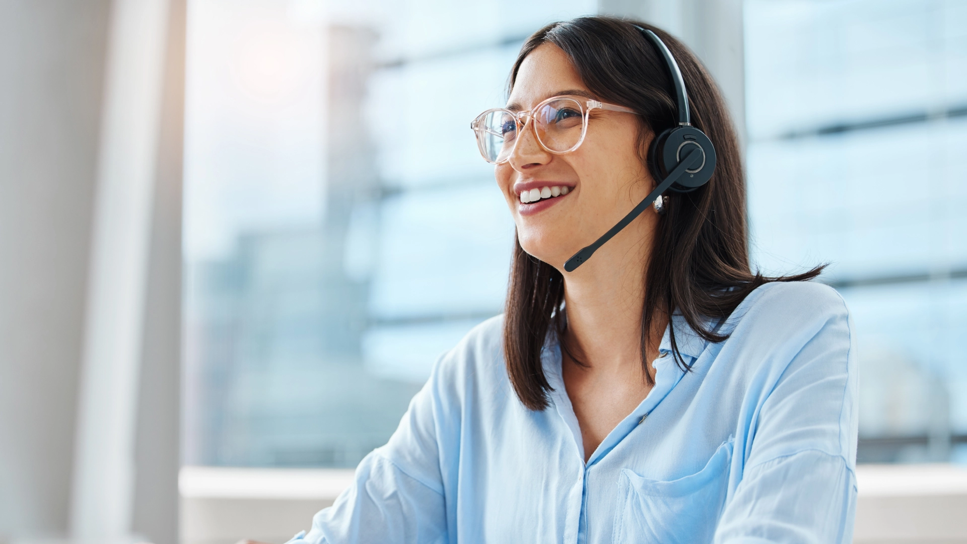 Smiling customer service agent wearing glasses and a headset, providing friendly and helpful support.