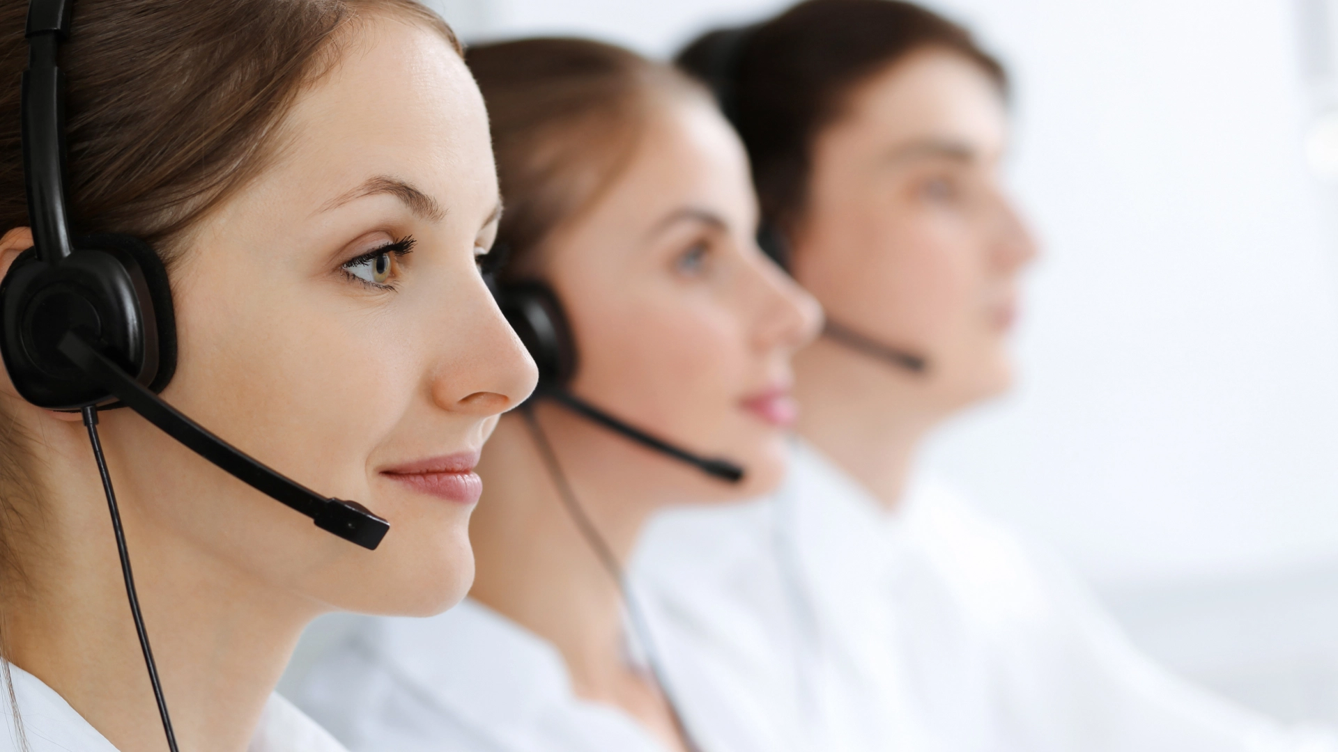 Three call center worker with headsets in the office.