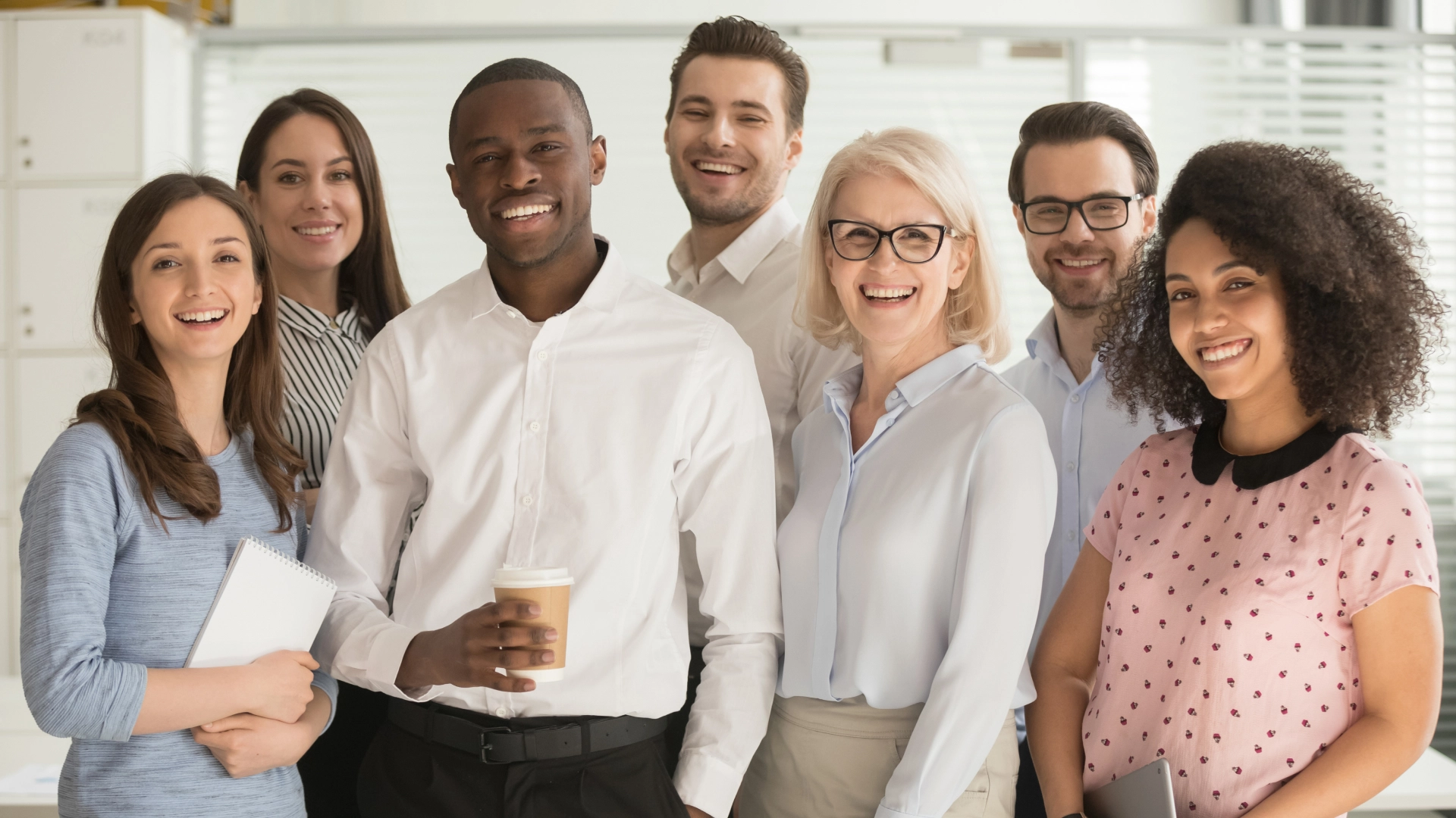 Smiling team of professionals standing together in an office setting.