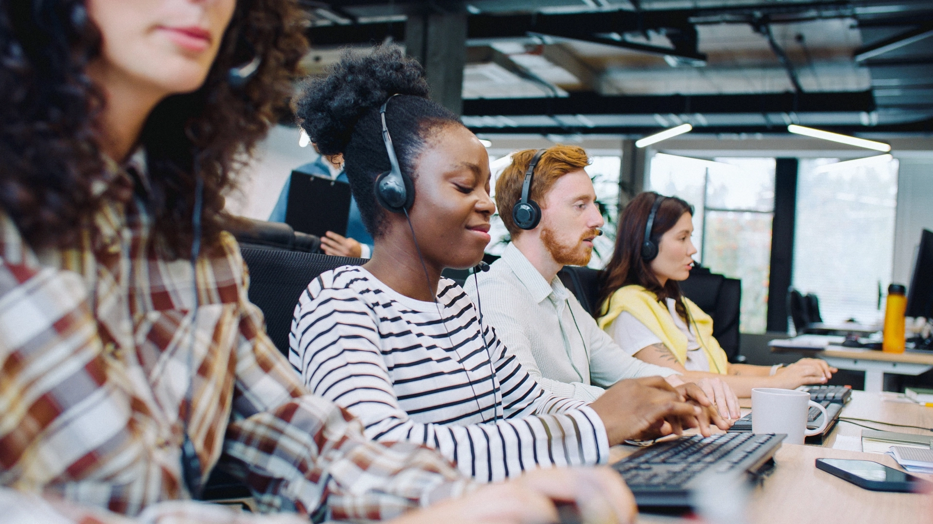 Team of customer service representatives wearing headsets and working in a call center.