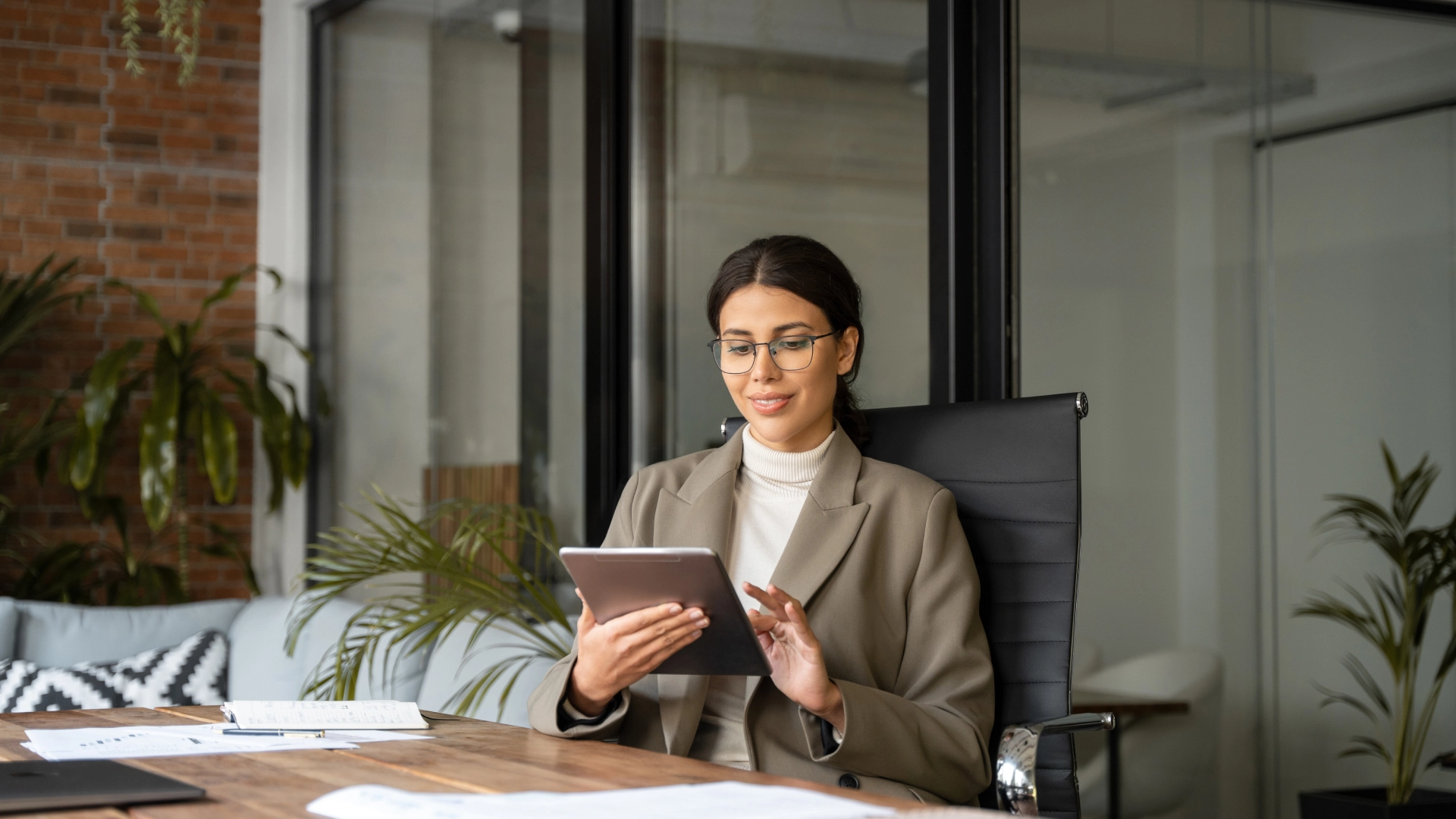Professional woman using a tablet in a bright, modern office environment.
