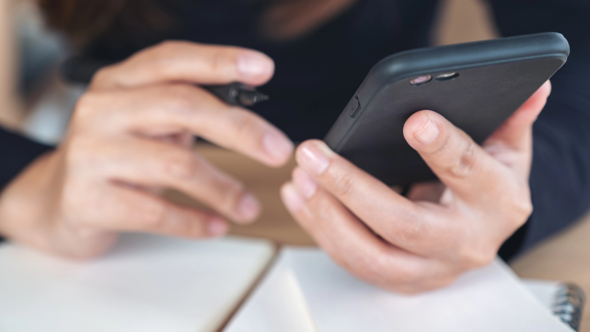 Person using a smartphone while taking notes